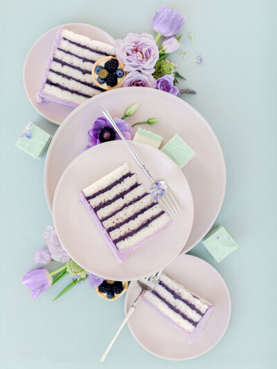 Pieces of wedding cake on plates with purple flowers and green background