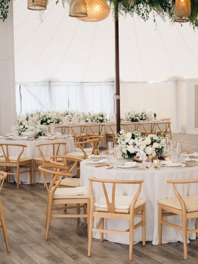 A bright and airy neutral wedding venue photo of the main dining area with brown chairs and white flowers during an alyssa amez design custom wedding