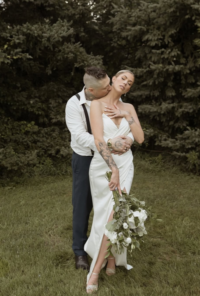 Bride and groom embracing while she holds her bouquet.