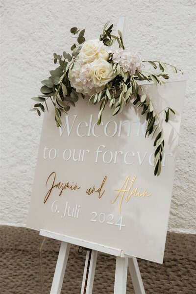 Schild zur Begrüssung der Hochzeitsgäste mit Blumendeko in Pastell