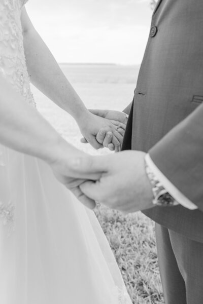 Groom holding his brides hand.  This Photo is in black and white.