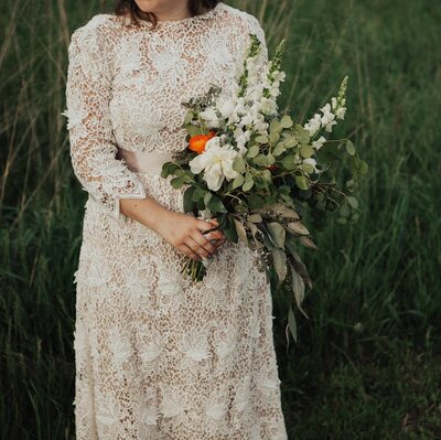 Bride in vintage wedding dress holding bouquet of natural greenery