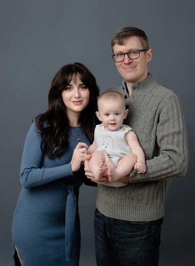 Family portrait of Mom, Dad & Baby boy looking at camera. Studio portrait was taken at Atlanta Photo Studio by Jenni Nikki Photography.