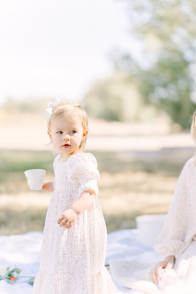Young toddler girl holds a tea cup during a session with Morgan Leigh Photography