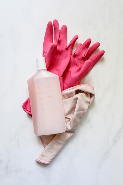 Pink cleaning gloves with a bottle of cleaning liquid