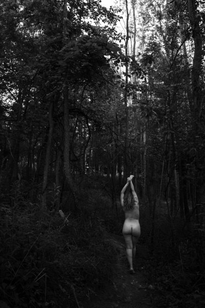 Woman standing nude in wooded area of Michigan, posing for an embodied feminine shoot with top boudoir photographer Magan Rogers.