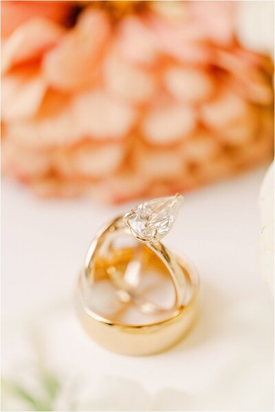 gold bride and groom's wedding bands with a large tear drop shaped diamond engagement ring