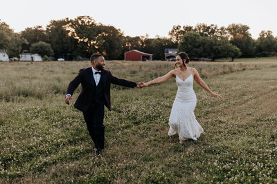 Destination Wedding Photographer captures bride and groom running through field together as husband and wife