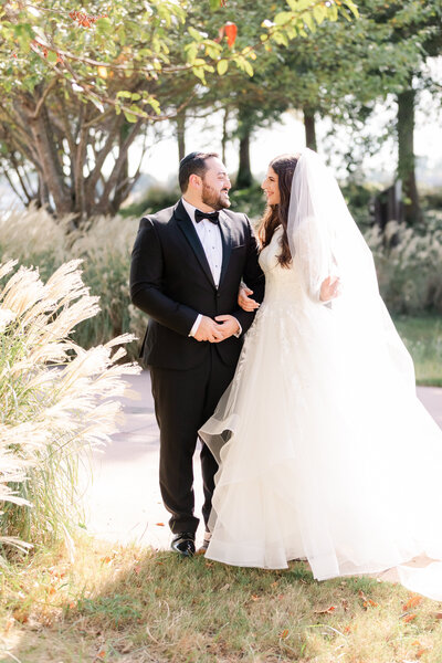 Bride and groom looking each other while bride holds veil.