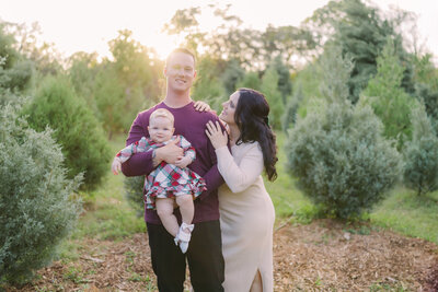 Couple holding baby in Blue Acres Christmas Tree Farm for Tampa Fall mini sessions.