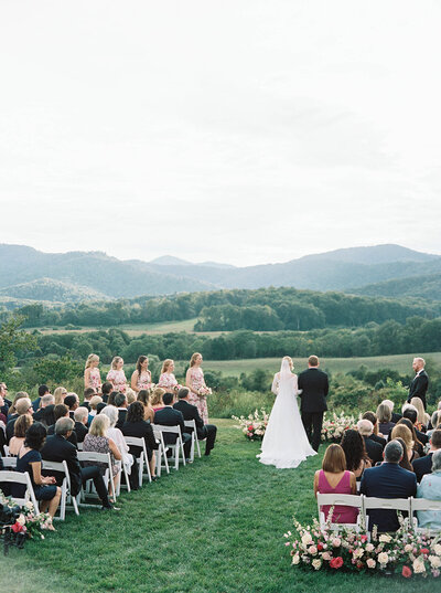 Outdoor wedding ceremony at vineyard with mountain views and seated guests overlooking the rolling hills

