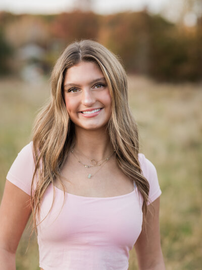 senior girl in pink shirt posing at park for senior photos