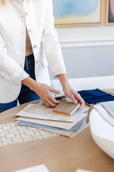 An interior design consultation in Frisco, featuring a professional using color pantones and fabric samples with various colors and textures. The consultant is dressed in a white blazer and blue jeans.