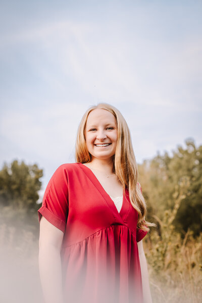 A young women in a red dress smiling.