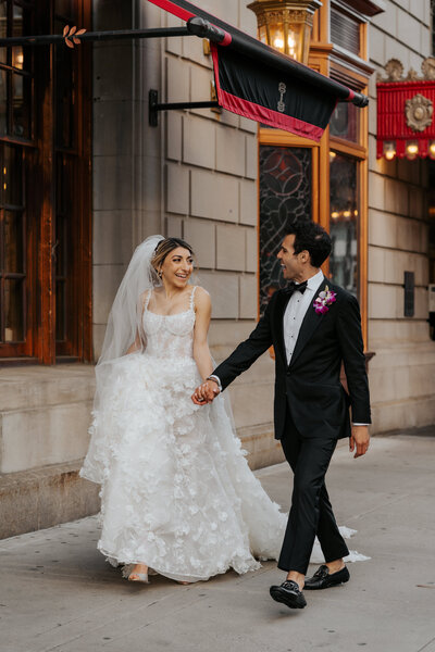 bride and groom holding hands while walking and smiling at each other