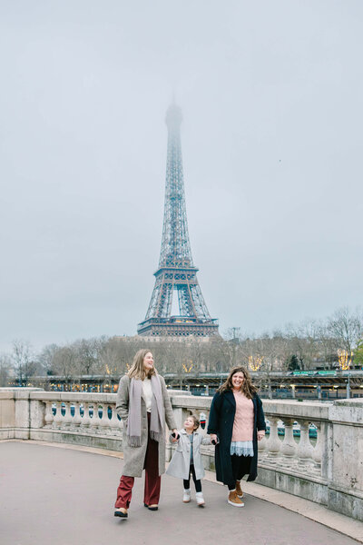 Family holding hands walking by Eiffel Tower on Paris Photoshoot Family Session by Rachael Laporte