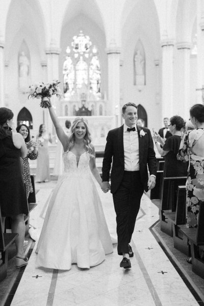 bride and groom leaving church ceremony with brides arm in the air