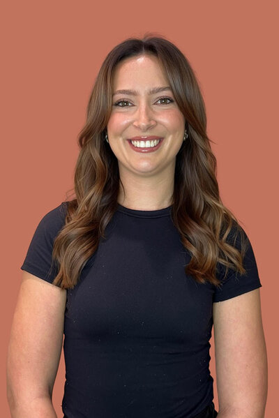 Kelsey, Female Senior hairstylist with balayage hair, dressed in a black tee.