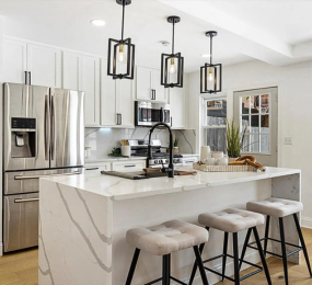 Expertly crafted modern kitchen remodel with a quartz waterfall island, custom shaker cabinets, stainless steel appliances, and bold black accents—showcasing quality craftsmanship and attention to detail.