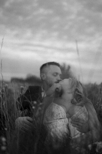black and white image couple kissing in field