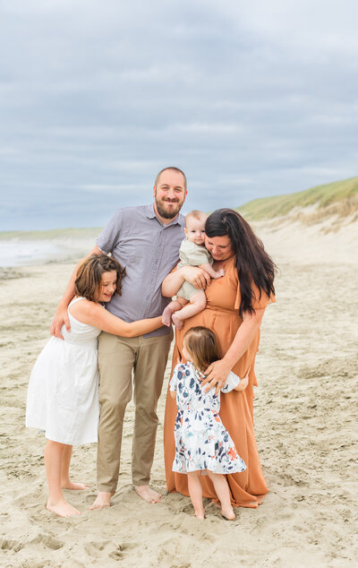 family smiling and hugging on an Oregon beach