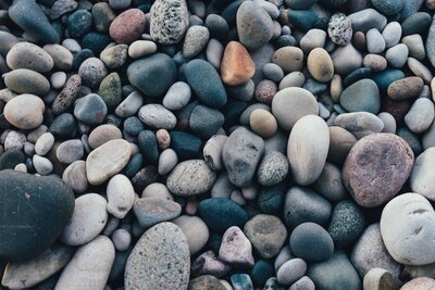 Small and medium rounded rocks on a beach. Photo by Scott Webb via Pexels.