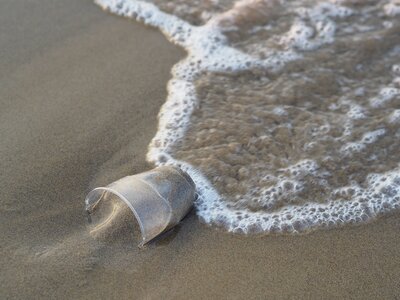 gobelet plastique échoué sur le sable d'une plage.