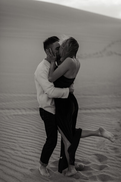 engaged couple kissing in the sand