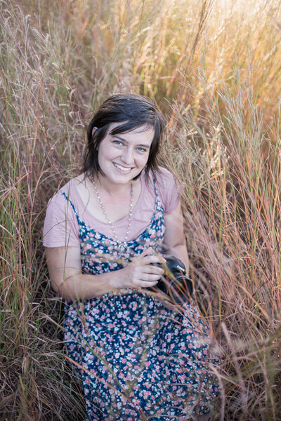 Stephanie, Loveland wedding photographer smiles at the camera in a field of golden rod.