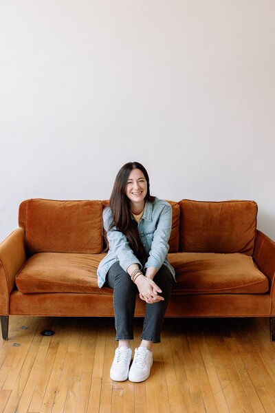 Melissa Stuckey sitting on a couch smiling