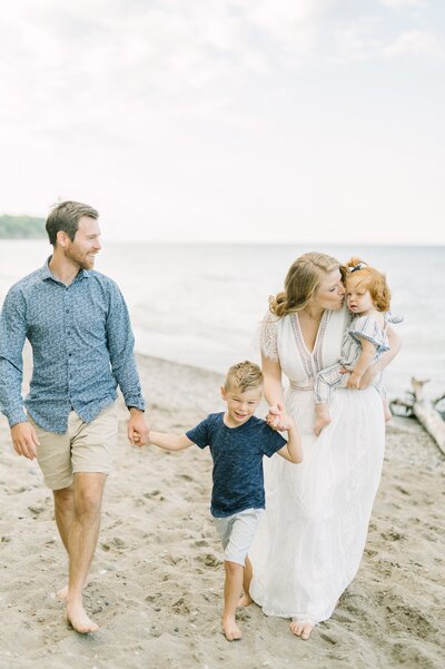 Family walking on beach smiling at Milwaukee maternity photoshoot