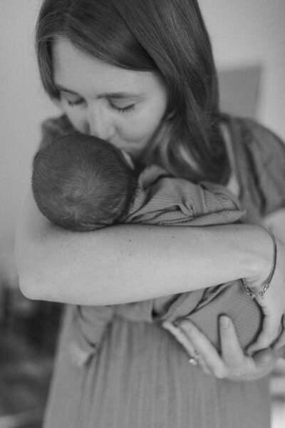 Mother gently kissing her baby's forehead, representing love, care, and the gift of parenthood.