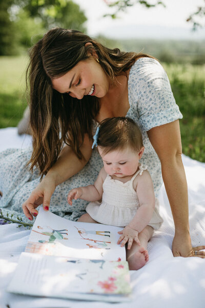 mother reading to her daughter outside on a picnic blanket