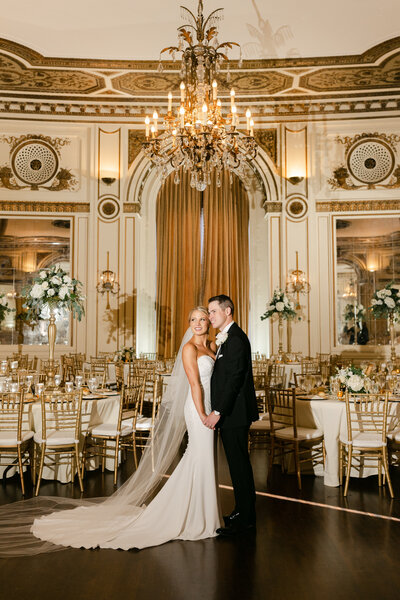 wedding couple pose inside luxury wedding ballroom