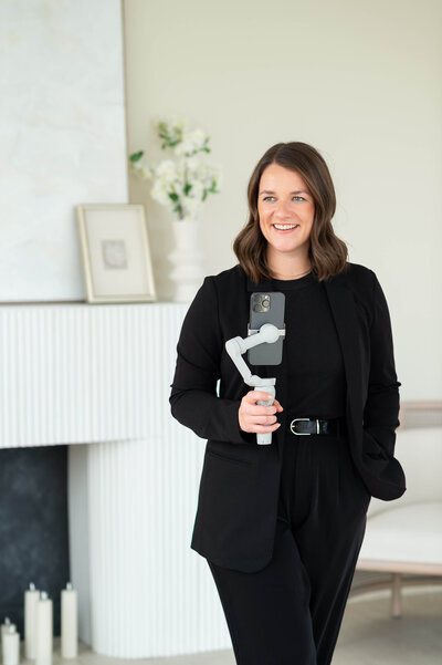 a profile photo of an Ottawa content creator in a black pantsuit holding a gimbal and an iphone