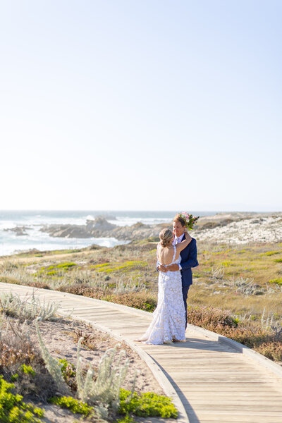 Bride and groom hugging on coastal trail in Monterey after wedding ceremony in Monterey,, photo by Anastasiya Photography - Monterey Wedding Photographer