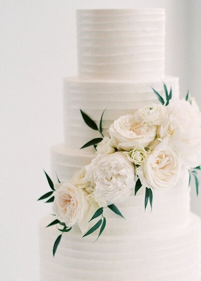 Elegant white luxury wedding cake topped with fresh white flowers at private estate in France