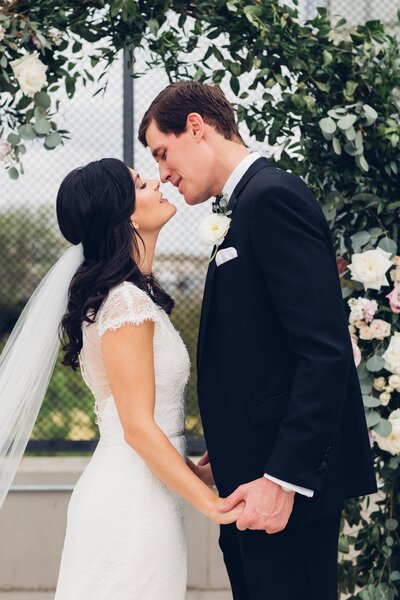 Destination wedding photography by Britt Elizabeth captures couple kissing passionately in front of a beautiful floral arch