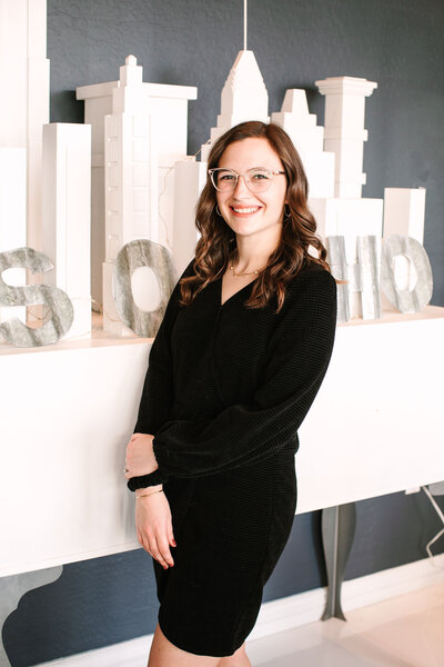 Megan Schmidt, CEO and owner of SoHo63, a Chandler wedding and event venue, smiles while posing indoors against a modern backdrop featuring neutral architectural decor. Her confident and welcoming presence reflects the leadership behind this popular Arizona event space.
