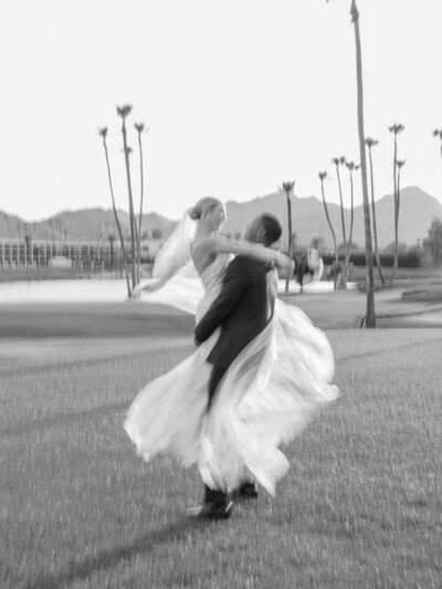 Romantic engagement photography capturing a joyful moment as a couple dances on a scenic Arizona golf course before their wedding.