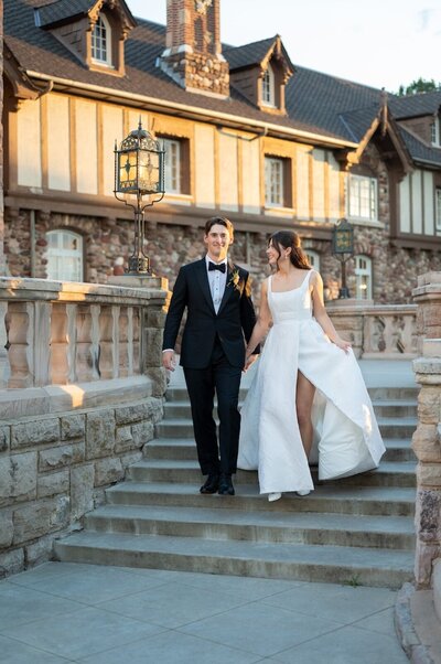 Couple walks down steps during golden hour at their summer wedding at Highlands Ranch Mansion.