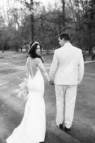 Bride and groom holding hands, with the bride looking back over her shoulder, capturing a romantic moment on their wedding day | Pittsburgh Wedding Photography
