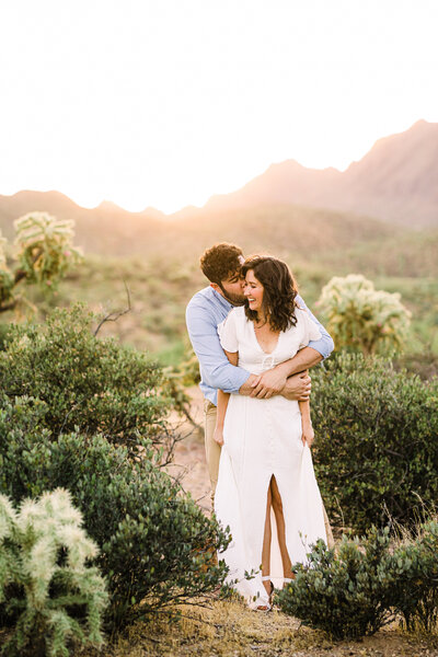 Engaged couple embracing in the sonoran desert at golden hour