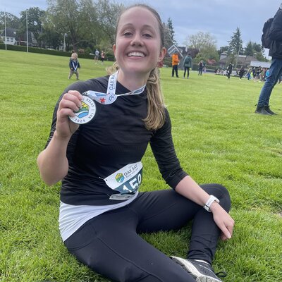 Woman runner with a medal, smiling after a competitive race, demonstrating success in racing goals
