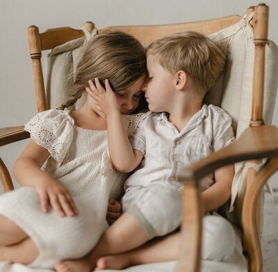 Siblings sharing a quiet moment on a chair photographed through Michigan photography