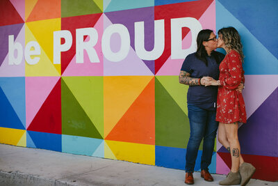 LGBTQ+ Couple posing at their front door showing just the bottom halves of them hugging surrounded by plants and a cactus
