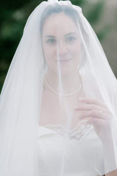 Stunning headshot of a bride under her blusher veil and looking at the camera. Image taken by Virginia wedding photographer, Rachael Mattio