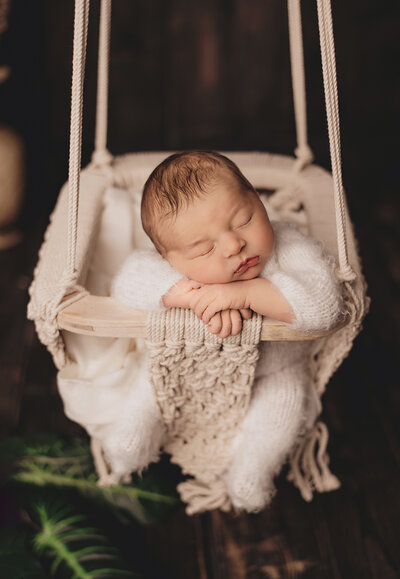 newborn boy sleeping upright in a macrame swing at his Hamilton, ON studio session.