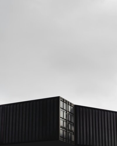 Two black and white shipping containers against sky