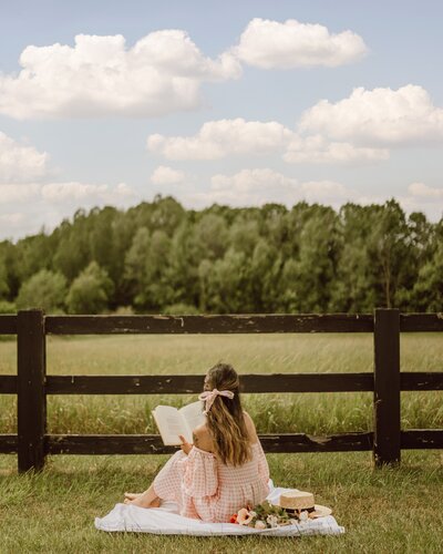 a-woman-reading-a-book-while-sitting-on-a-picnic-blanket